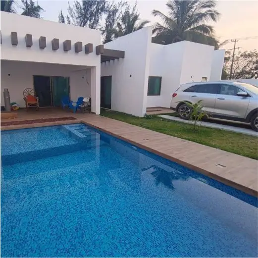 Área de estacionamiento privado seguro junto al jardín y la alberca frente a la moderna fachada blanca de Villa Tortuga en Costa Esmeralda