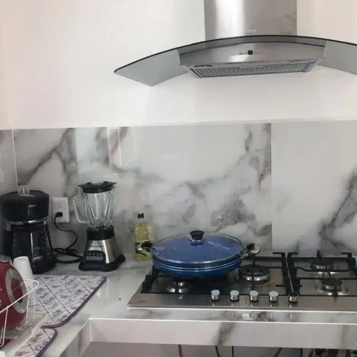 Cocina completamente equipada en Villa Tortuga con estufa de gas moderna, campana extractora de cristal, cafetera, licuadora, olla azul y acabados de mármol.