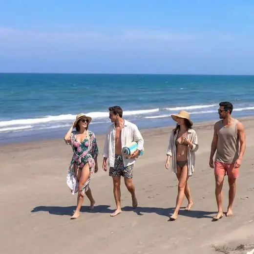 Grupo de amigos caminando relajados por la playa de arena frente al mar, disfrutando del acceso privado cerca de Villa Tortuga en Costa Esmeralda, Veracruz.