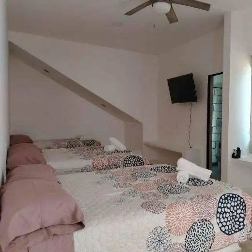 Habitación climatizada en Villa Tortuga con aire acondicionado split y ventilador de techo, camas ordenadas y toallas.